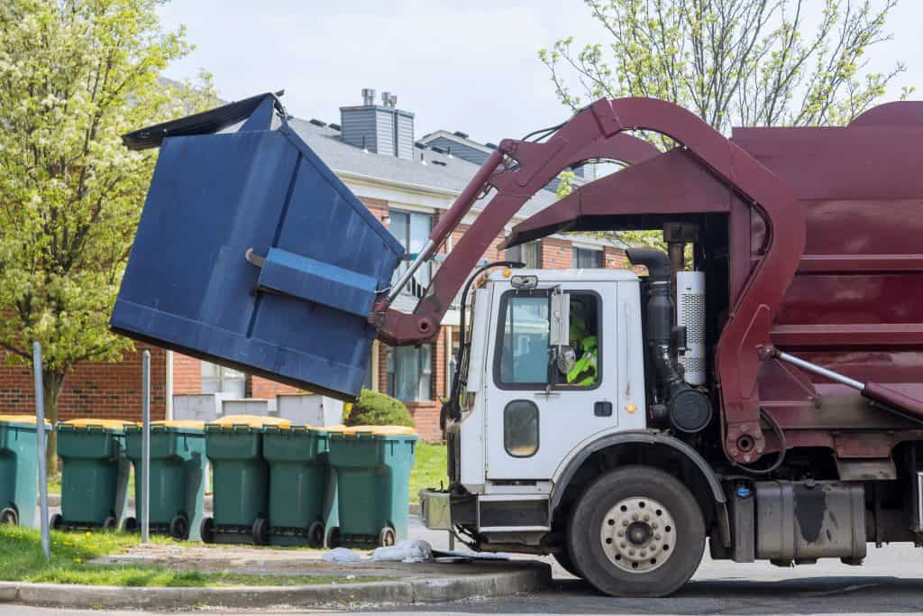 Front Load Garbage truck (red) picking up blue dumpster