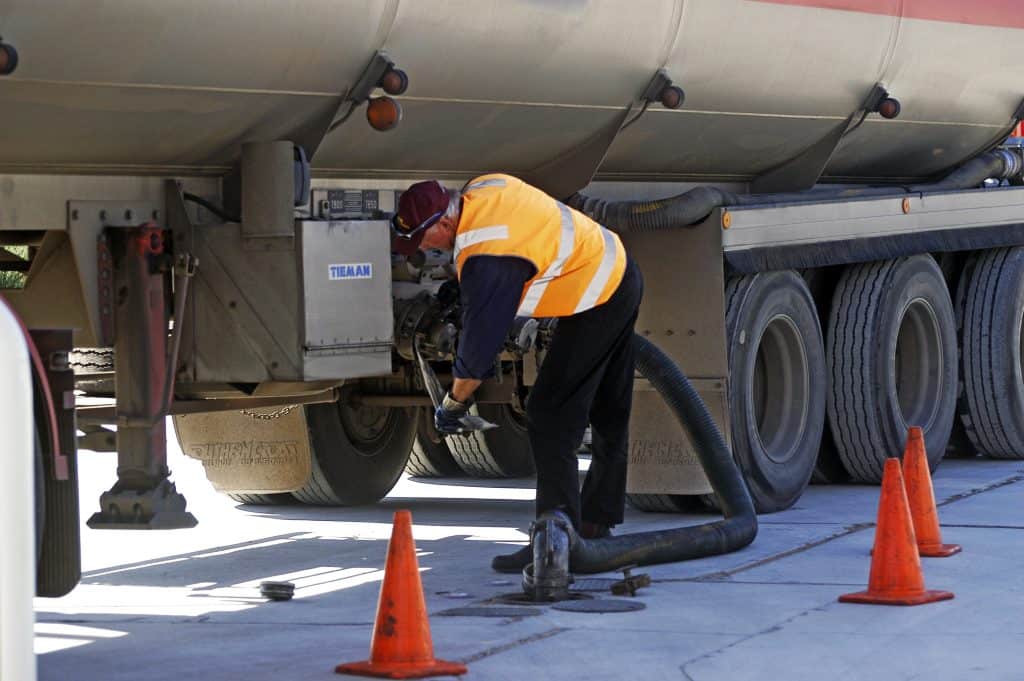 Truck Driver setting up to deliver fuel to gas station