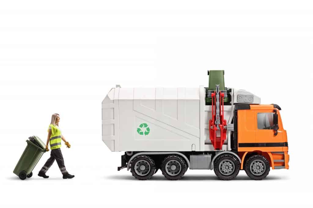 Female waste collector pulling a bin towards a garbage truck