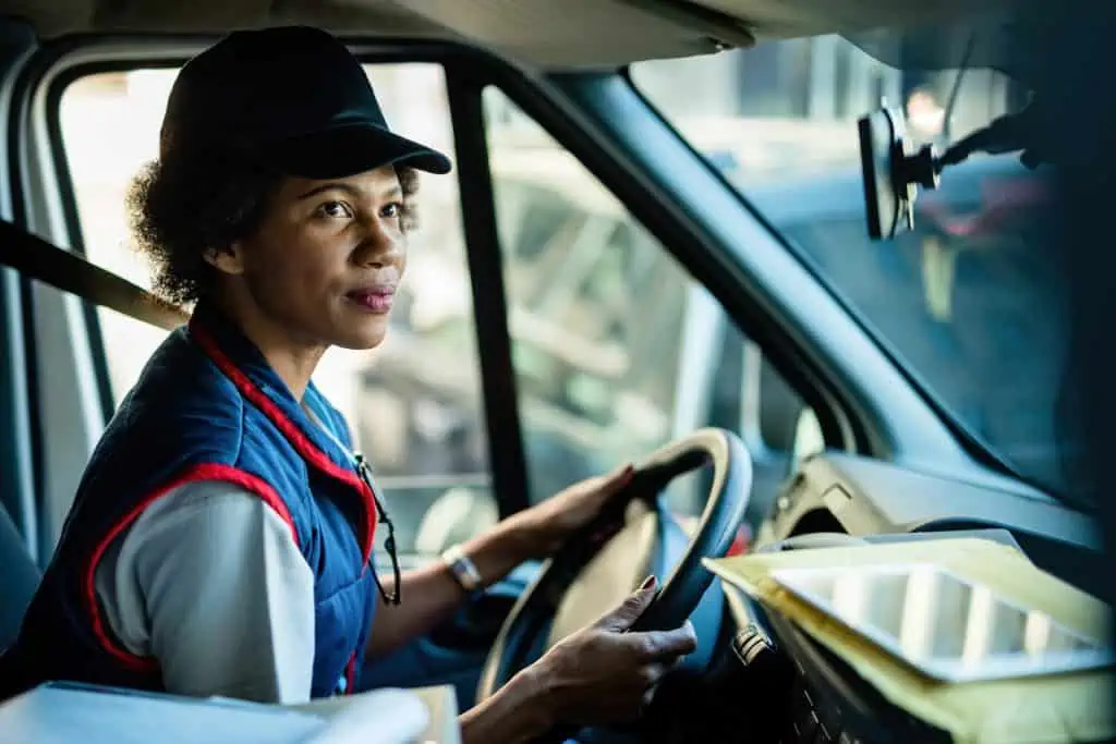 african american female courier driving delivery van city