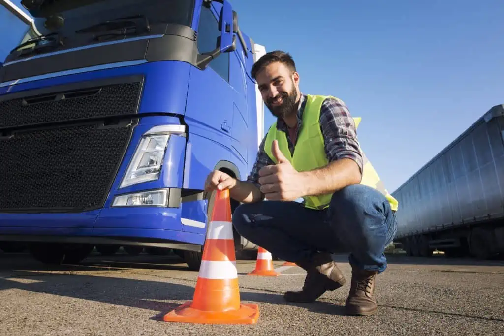 Man standing next to a truck with traffic cones.