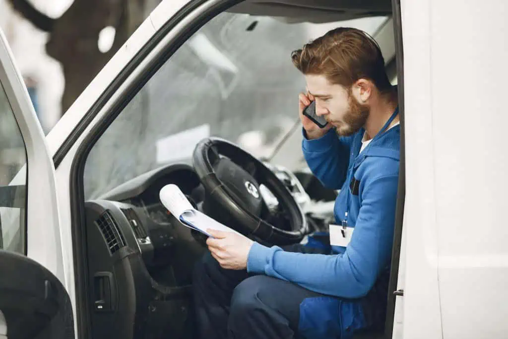 Man checking notepad while talking on his phone in a truck.