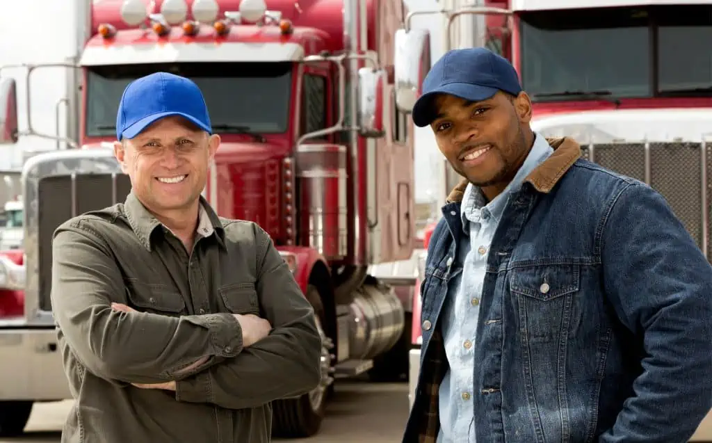 Two men standing in front of trucks.