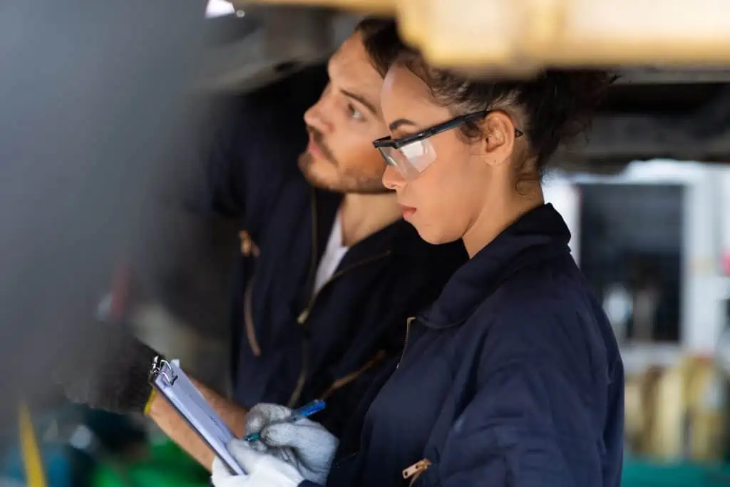 Hispanic Female trainee Mechanics Working Underneath Car Together