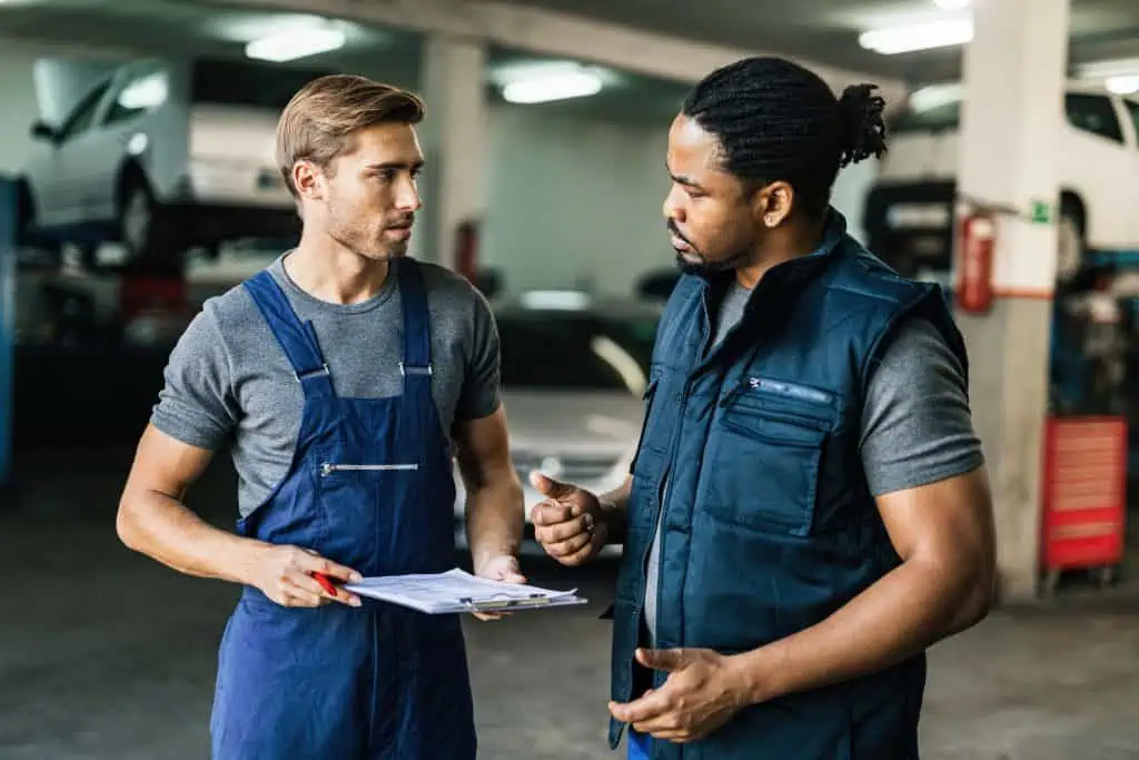 African American car mechanic and his manager communicating in auto repair shop.