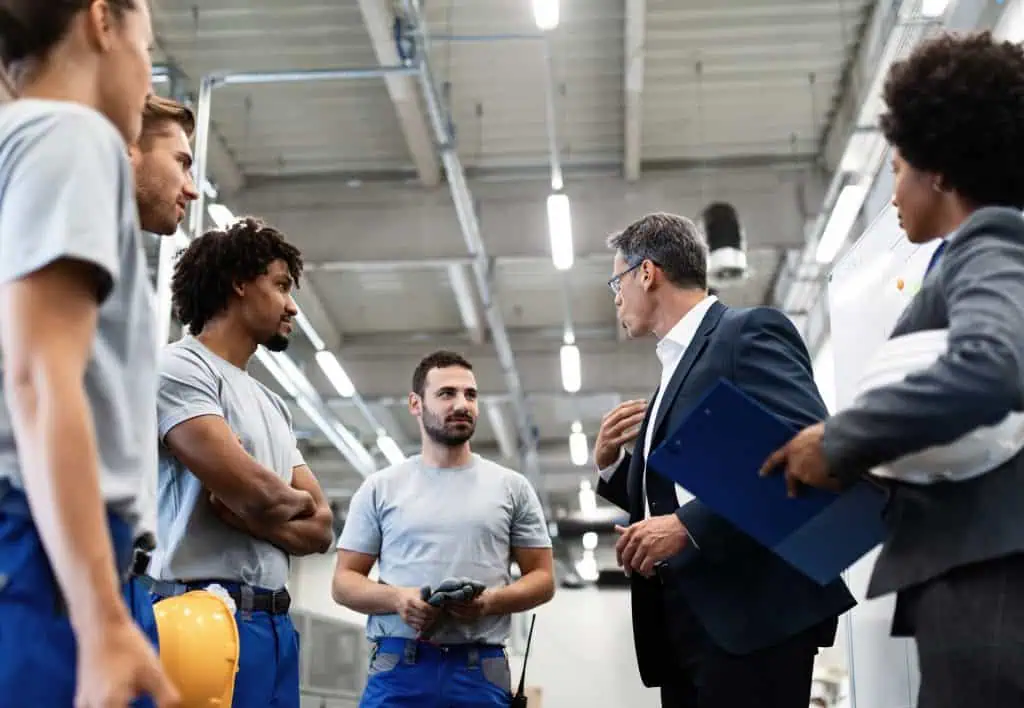 low angle view businessman talking with team manual workers while having staff meeting industrial plant1