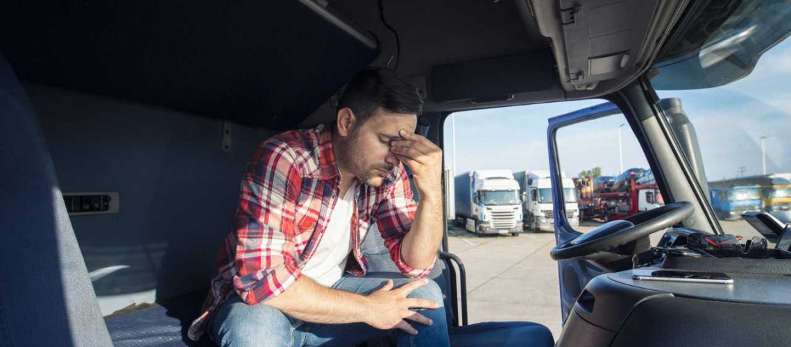 Truck driver sitting in his truck cabin feeling worried and upset.